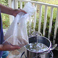 Person holding a bag of grains near a pot of water on a porch.