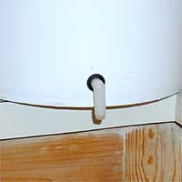 White bucket with a small drainage port, mounted on a light wooden surface.